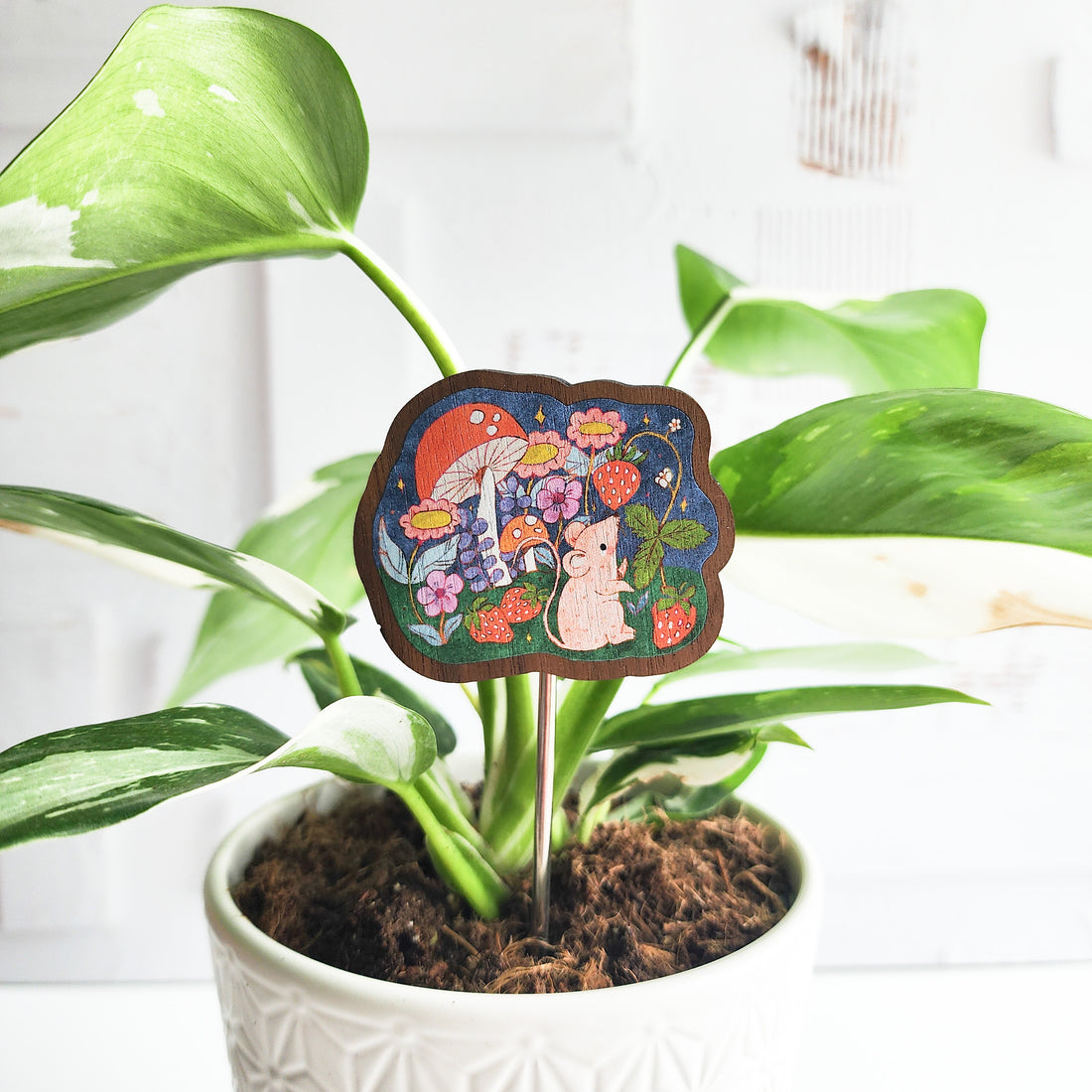 mouse decorative plant pick inside of a houseplant against a white brick background