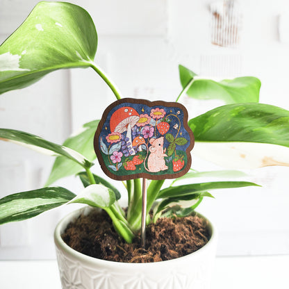 mouse decorative plant pick inside of a houseplant against a white brick background