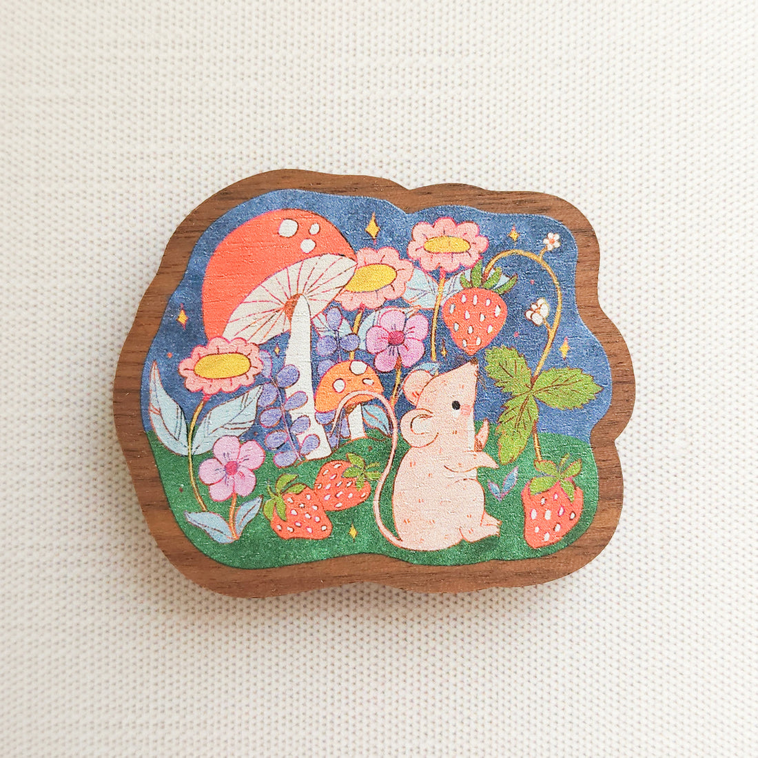 wooden magnet with an illustration of a mouse picking strawberries on a linen background