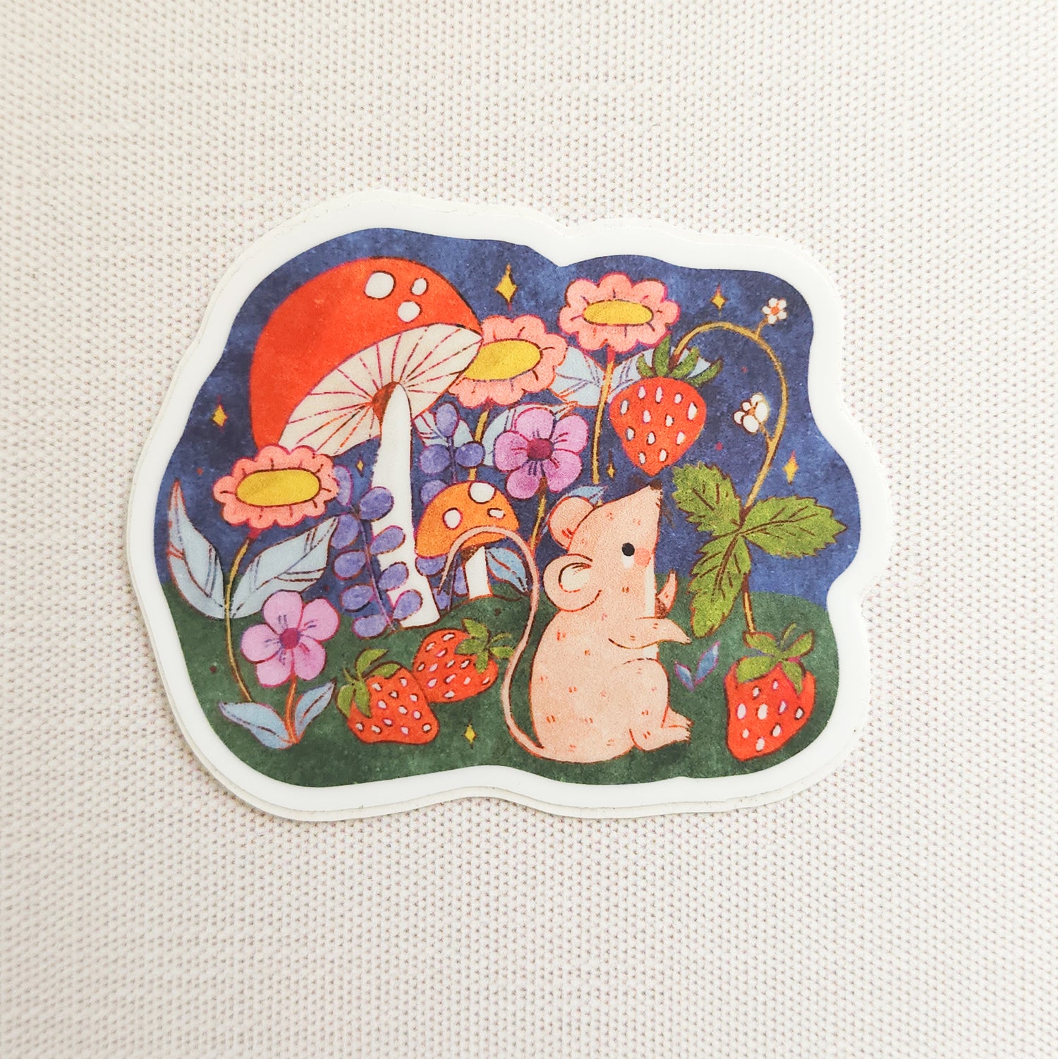 sticker of an illustrated mouse picking strawberries on a linen background