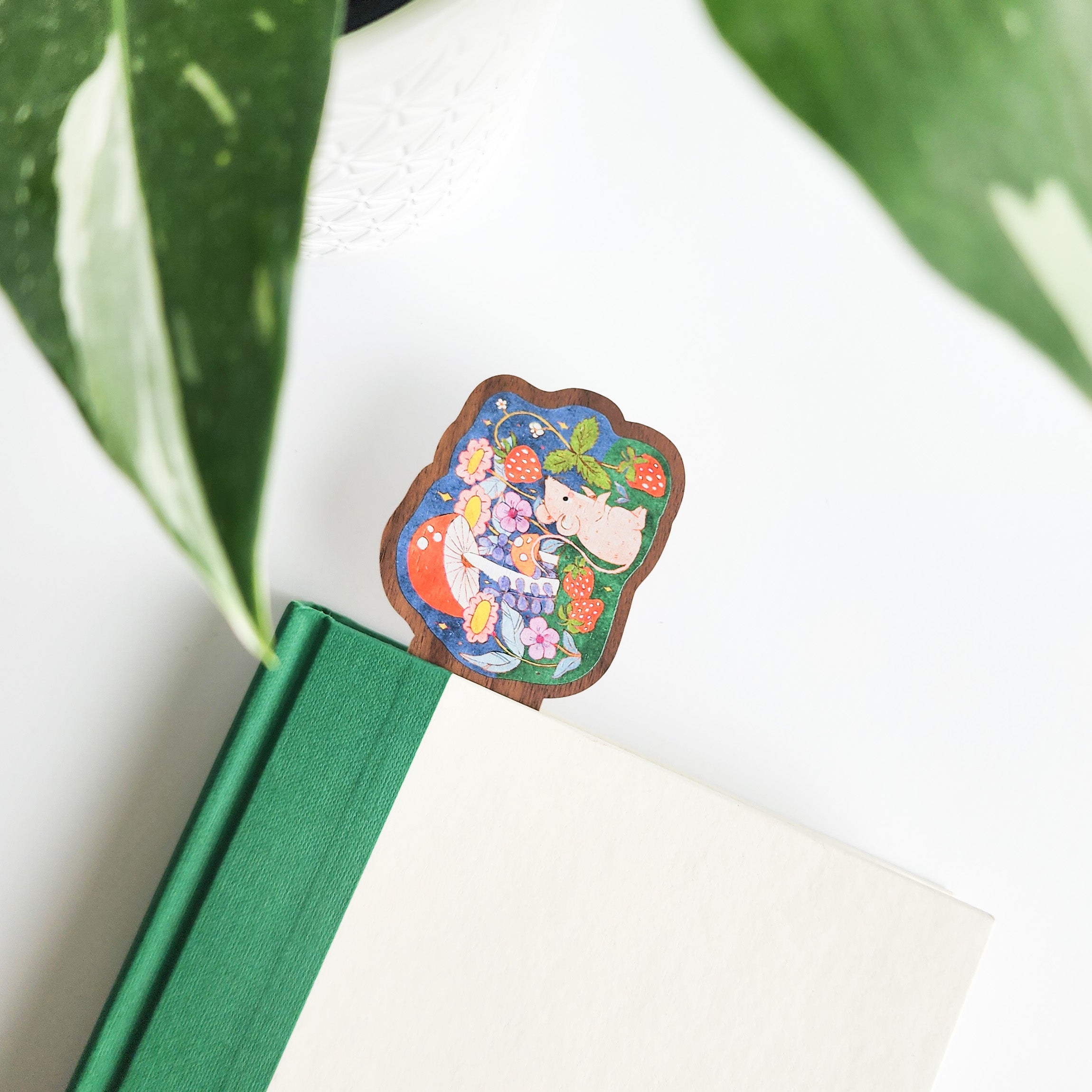 mouse bookmark in a green and white book on a white background with leaves