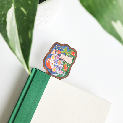 mouse bookmark in a green and white book on a white background with leaves