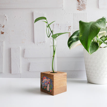 wooden propagation station with a mouse picking strawberries. There is a green plant cutting in a glass tube on a white background