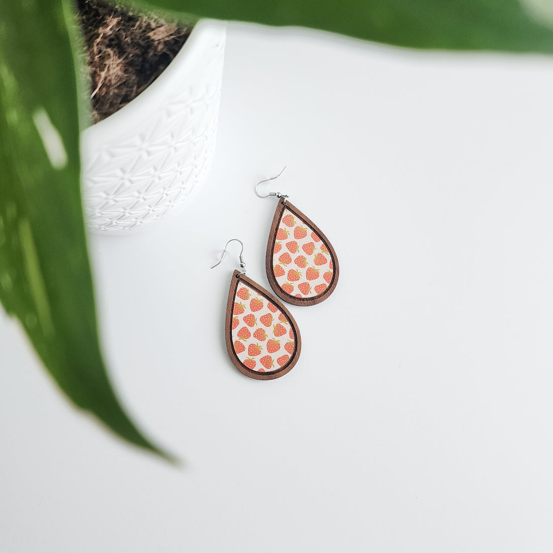 strawberry earrings on a white background with a potted plant