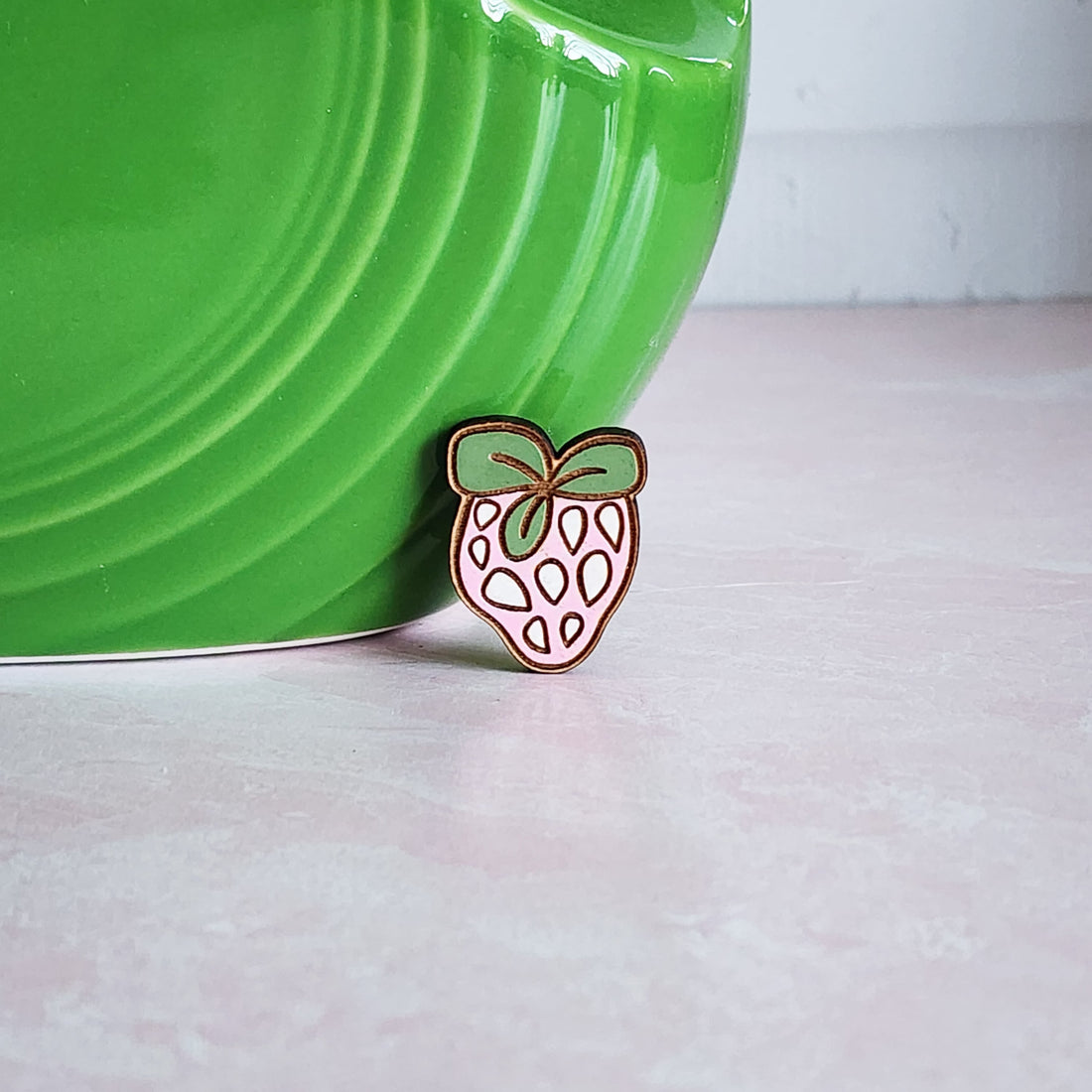 ink and green strawberry pin in front of a green case