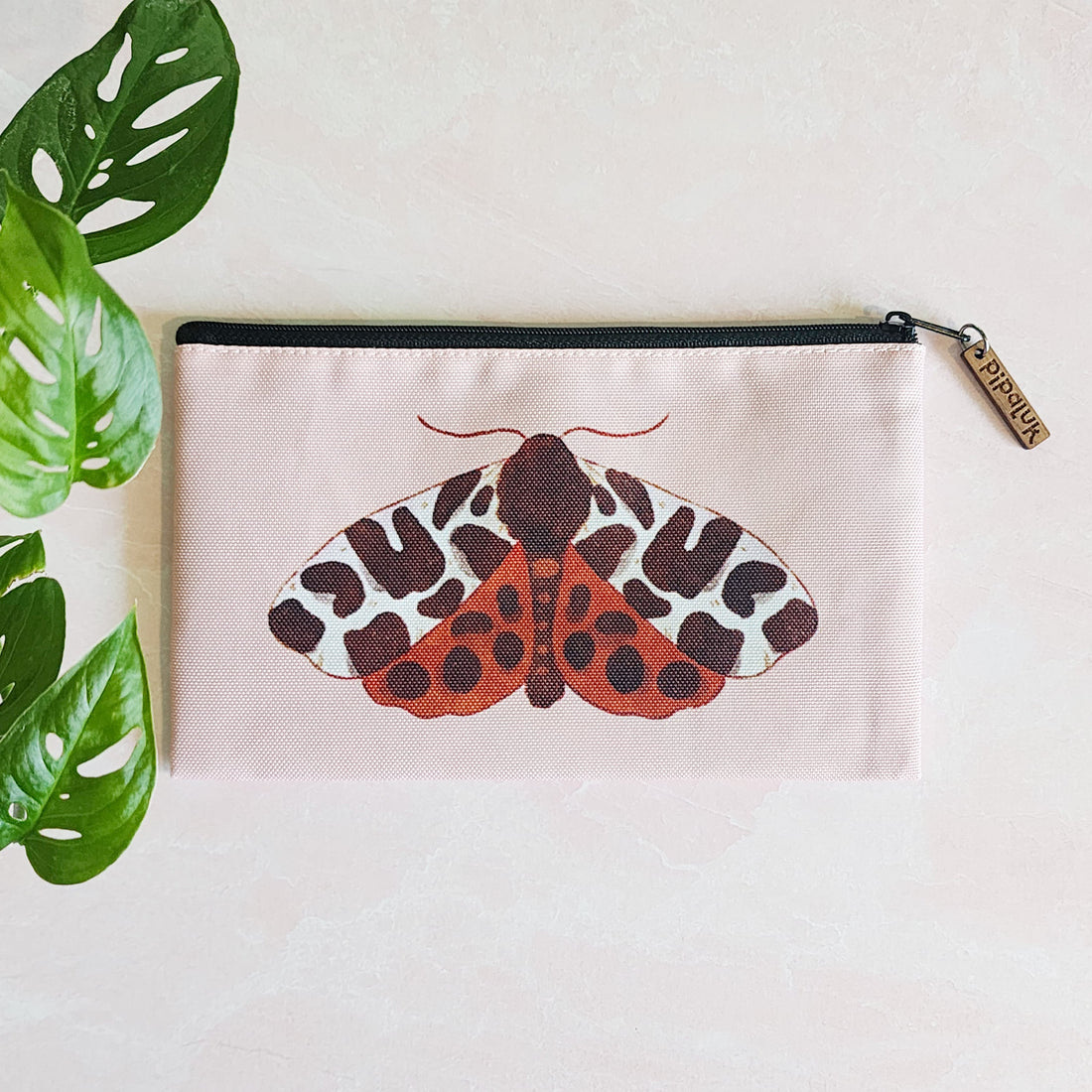 zipper pouch with a tiger moth on a pink background